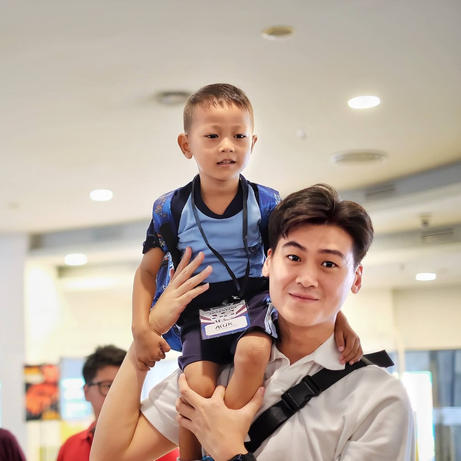 Volunteer carrying a student on his shoulders
